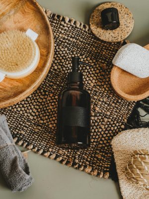 Flat lay of natural skincare products and accessories on woven mat for body care.
